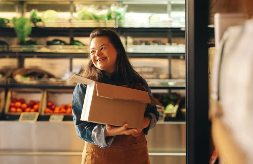 Disabled girl with down syndrome in grocery store smiling while holding box