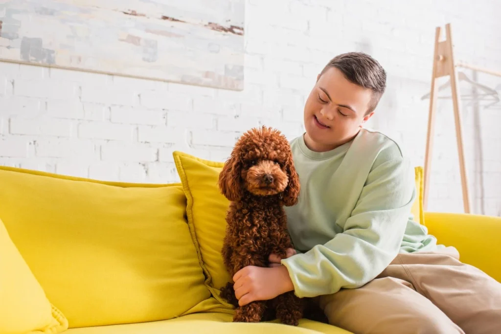 Disabled man with down syndrome sitting on couch with dog
