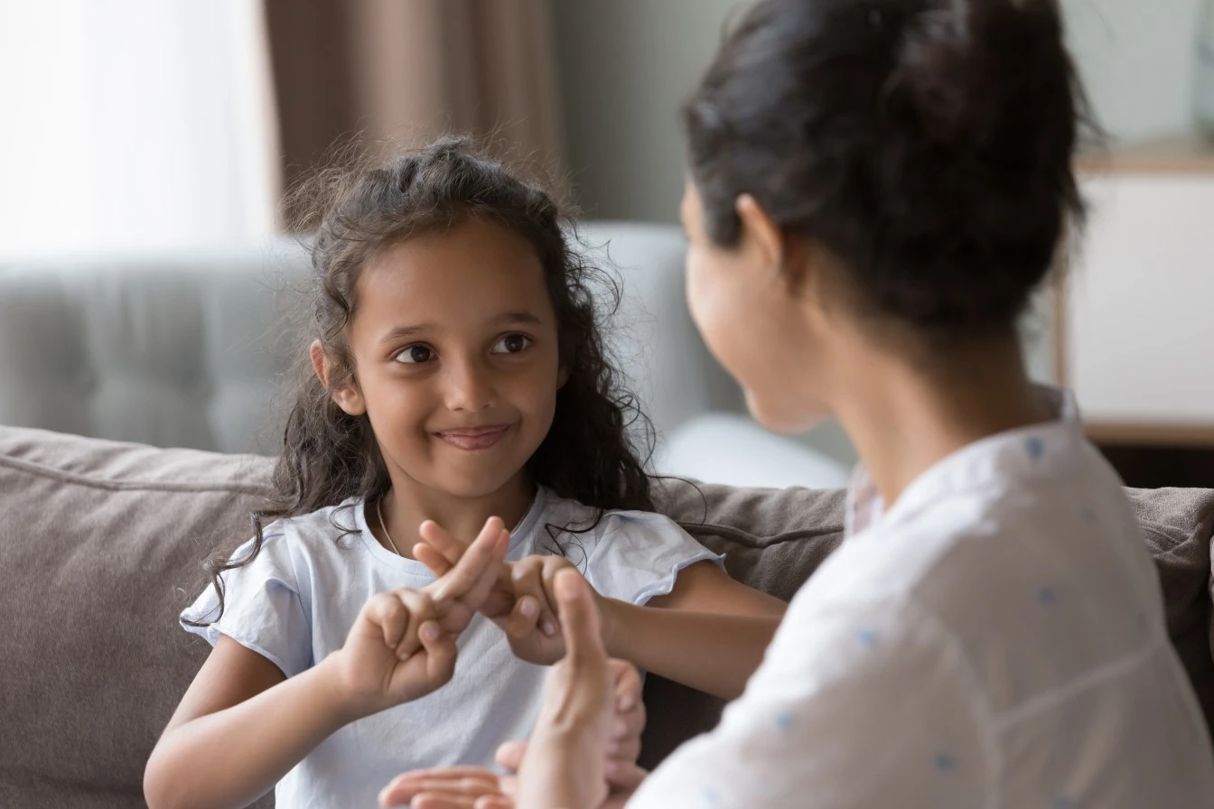 Young deaf child learning sign language with a support worker