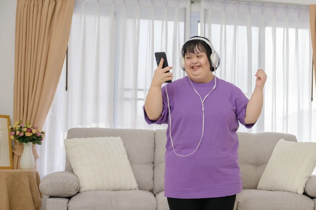 Disabled girl standing in living room with headphones listening and dancing to music